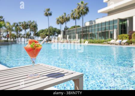 Frischer roter Cocktail mit Eis im Glas im Swimmingpool. Tropischer Saft bei Luxusurlauben. Konzept Sommerurlaub und Reisen Stockfoto