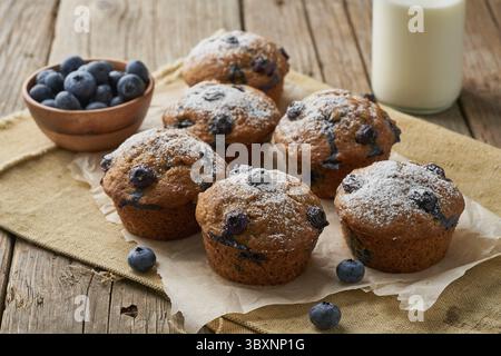 Blaubeer-Muffin, Seitenansicht. Cupcakes mit Beeren auf alter Leinenserviette, rustikaler Holztisch, Frühstück mit Kuchen Stockfoto