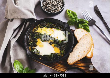 Essen, Grüne gebackene Shakshuka mit Kräutern in einer Pfanne auf dem Tisch Stockfoto