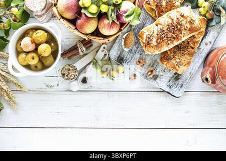 Essen, Backen mit Apfel, frisch gebackener Apfel und Zimtrollen aus Blätterteig auf weißem Tisch Stockfoto