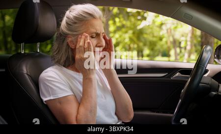 Gestresste besorgte Kaukasier leiden ältere ältere ungesunde Frau ältere Autofahrerin Dame mit Kopf massierende Schläfen leiden unter Kopfschmerzen Stockfoto