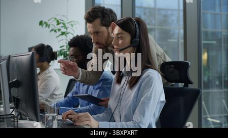 Multiethnische Callcenter Teamwork Support Service Kaukasischer Mann Manager Tablet Zeigescreen Headset Helpdesk Frau Angestellte afrikanisch-indische Kollegen Stockfoto