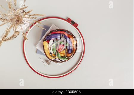Food, Scissors on basket with colored embroidery threads in hoops on gray background top view Stockfoto