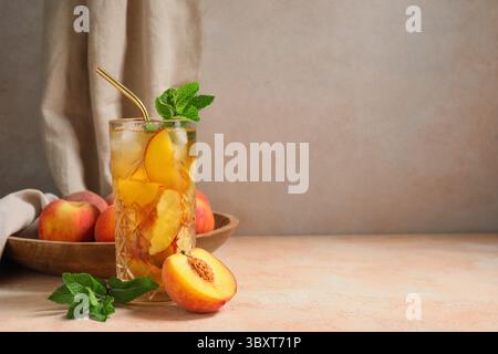 Glas leckerer Pfirsicheistee auf rosa Grunge Hintergrund, Nahaufnahme Stockfoto