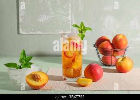 Glas leckerer Pfirsicheistee auf grünem Grunge-Hintergrund, Nahaufnahme Stockfoto