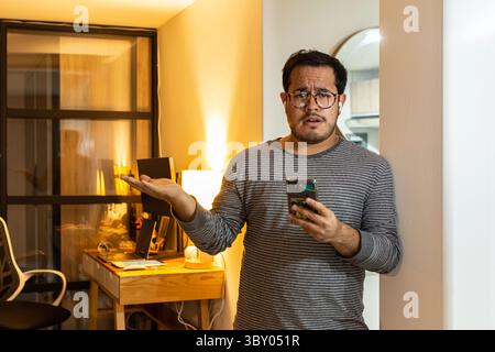 Besorgter Unternehmer, der schlechte Nachrichten am Telefon im Home Office liest Stockfoto