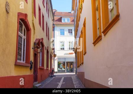 Heidelberg, Deutschland - 21. Juni 2025: Enge, lebhafte Gasse in Heidelberg, mit farbenfrohen Gebäuden und einem Geschäft. Stockfoto
