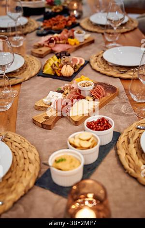 Eine elegante Wurstplatte gefüllt mit verschiedenen Käsesorten, Aufschnitt und Früchten, wunderschön auf einem rustikalen Tisch angeordnet, perfekt für einen Gourmet-di Stockfoto