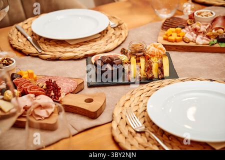 Ein elegant gestalteter Esstisch mit Wurstplatte und Obstplatte mit einer exquisiten Auswahl an Käse, Nüssen und Wurstwaren. Stockfoto