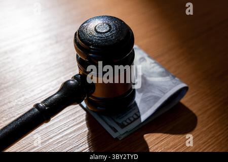 Ein Stapel US-Dollar-Scheine und ein Hammer. Bestechung, Korruption oder legale Geschäfte mit dem Konzept „Geld“. Stockfoto