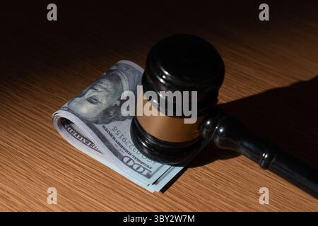 Ein Stapel US-Dollar-Scheine und ein Hammer. Bestechung, Korruption oder legale Geschäfte mit dem Konzept „Geld“. Stockfoto