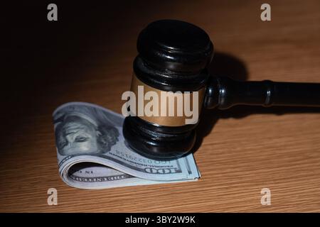 Ein Stapel US-Dollar-Scheine und ein Hammer. Bestechung, Korruption oder legale Geschäfte mit dem Konzept „Geld“. Stockfoto