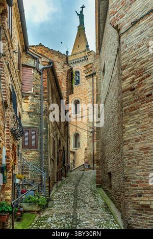 Eine mittelalterliche Straße, die von Backsteinhäusern gesäumt ist, führt zur Kathedrale der Heiligen Gregor und Margarete in Ripatransone. Ripatransone, Ascoli Piceno, Marken Stockfoto