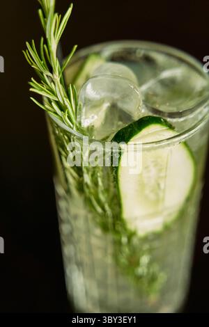 Ein erfrischender Cocktail mit Gurkenscheiben und Rosmarinzweigen in einem Glas mit Eiswürfeln bietet ein knackiges und aromatisches Kräutergetränk Stockfoto