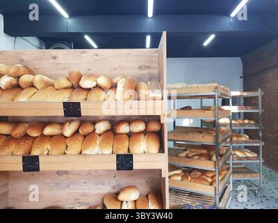 Gebackenes Brot in Holzregalen in einer Bäckerei mit warmen knusprigen Brotlaiben, die den Gästen köstliche Brotprodukte bieten Stockfoto
