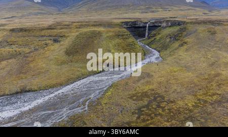 Aus der Vogelperspektive auf einen hohen Wasserfall und Fluss, der durch Gras zwischen sanften Hügeln fließt, Ekmanfjord, Svalbard, norwegische Arktis, Europa Stockfoto