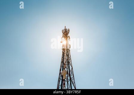Telekommunikations-TV-Antennen mit Handy-Antennen und Satellitenschüssel mit blauem Himmel im Hintergrund Stockfoto