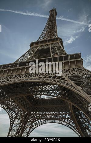 Blick von unten auf den Eiffelturm im eisernen und Jugendstilstil mit sonnigem blauem Himmel in Paris. Bekannt als die Stadt des Lichts, ist eine der beeindruckendsten Stockfoto