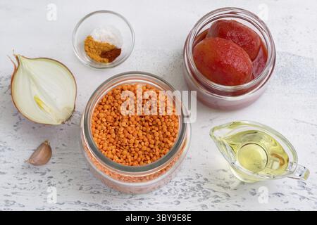 Lebensmittel, Zutaten für vegane Tomatensauce, Suppe oder für Linsenpfannkuchen: Rote Linsen, Zwiebeln, Knoblauch, Dosentomaten, Gewürze und Pflanzenöl o Stockfoto