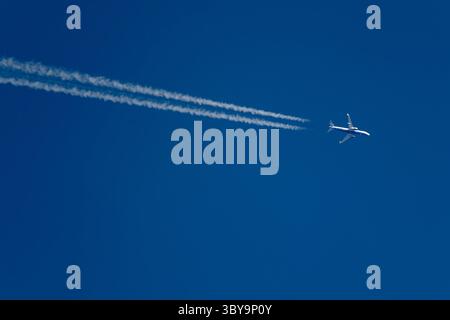 Ein Ryanair-Flugzeug, das in großer Höhe gegen einen klaren blauen Himmel mit Kondensstreifen hinter dem Flugzeug mit Kopierraum fliegt. Stockfoto