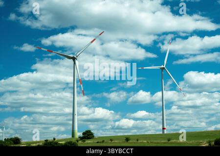 Moderne Windturbinen, die in einer ländlichen Landschaft stehen und saubere und erneuerbare Energie als Teil eines Windparks erzeugen. Die Szene stellt eine nachhaltige Energieerzeugung und den Übergang zu umweltfreundlichen Energiequellen dar. Stockfoto