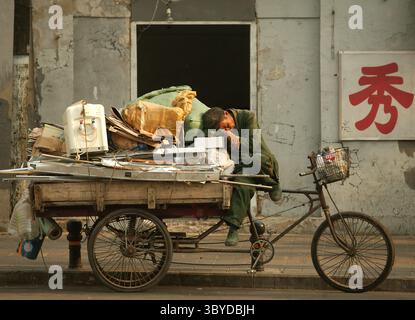 14. Mai 2009, PEKING, CHINA: Ein chinesischer Migrant, der recycelbaren Müll sammelt, macht am 14. Mai 2009 in Peking ein Nickerchen auf seinem „Flachbett“-Dreirad. Während China nach Jahren des umweltschädlichen Wachstums Dutzende Milliarden in die Sanierung investiert, kämpfen große und kleine Unternehmen um Verträge, um verschmutzte Wasserstraßen und Deponien wiederherzustellen. (Bild: © Stephen Shaver/ZUMA Press Wire) Stockfoto