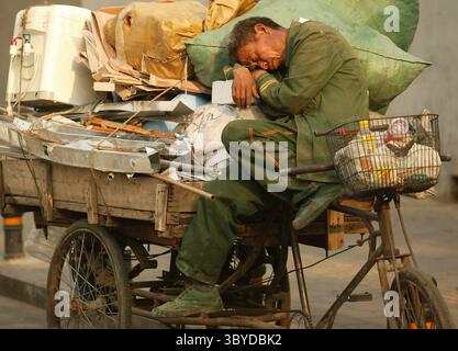 14. Mai 2009, PEKING, CHINA: Ein chinesischer Migrant, der recycelbaren Müll sammelt, macht am 14. Mai 2009 in Peking ein Nickerchen auf seinem „Flachbett“-Dreirad. Während China nach Jahren des umweltschädlichen Wachstums Dutzende Milliarden in die Sanierung investiert, kämpfen große und kleine Unternehmen um Verträge, um verschmutzte Wasserstraßen und Deponien wiederherzustellen. (Bild: © Stephen Shaver/ZUMA Press Wire) Stockfoto