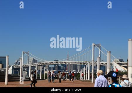 Das tägliche Leben in Japan Odaiba Promenade mit Blick auf den Tokyo Tower und die Tokyo Rainbow Bridge, mit Touristen, die kommen und gehen Stockfoto