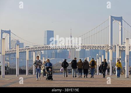 Das tägliche Leben in Japan Odaiba Promenade mit Blick auf den Tokyo Tower und die Tokyo Rainbow Bridge, mit Touristen, die kommen und gehen Stockfoto