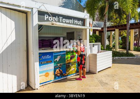Die Frau kehrt zurück und erhält Strandtücher in der Poolhandtuchhütte im tropischen Resort. Dominikanische Republik. Punta Cana. Stockfoto