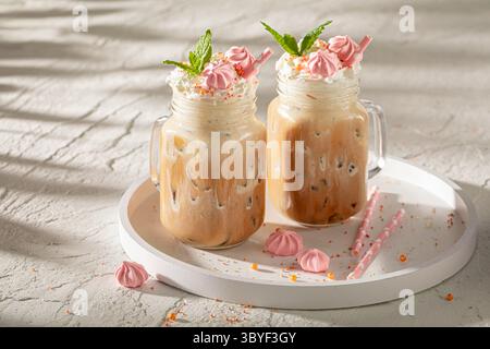 Köstlicher und süßer Eiskaffee im Glas mit Strohhalm. Frappuccino mit Streuseln und Sahne. Stockfoto