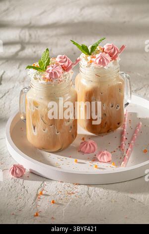 Kalter und leckerer Eiskaffee im Glas mit Strohhalm. Frappe mit Schlagsahne. Stockfoto