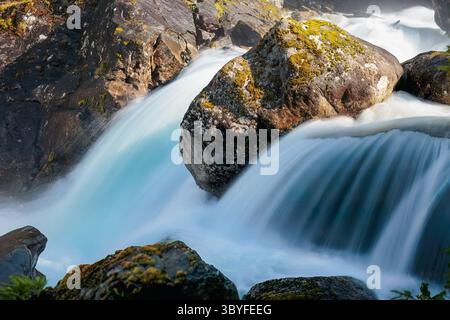 Nahaufnahme eines Gebirgsbaches, der über moosige Felsen in Geiranger, Norwegen rauscht. Schnelles Wasser, weiches Licht, reine skandinavische Natur. Stockfoto