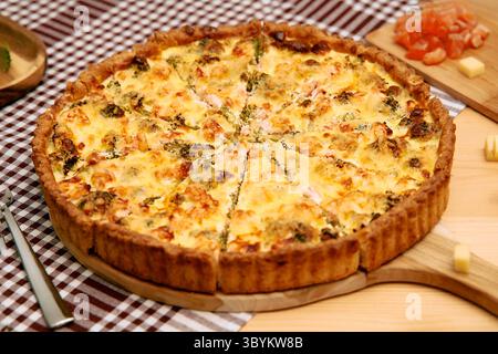 Eine perfekt gebackene, hausgemachte Quiche mit frischem Brokkoli und Käse, serviert auf einer rustikalen karierten Tischdecke und präsentiert seine einladende und herzhafte App Stockfoto