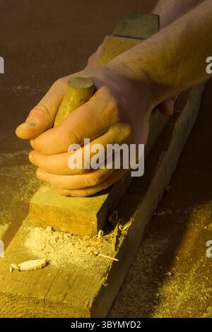 Nahaufnahme der Hand am Handflugzeug auf Holz, der Schreiner Hand am Flugzeug Werkzeug Stockfoto
