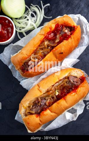 Flaches Lay-Bild traditioneller südafrikanischer Boerewors-Rollen. Frisch und lecker garniert mit Tomatenrelish und Zwiebeln Stockfoto