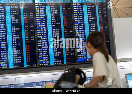Hongkong, China. Juli 2025. Passagiere überprüfen die Fluginformationen am Hong Kong International Airport in Hong Kong, Südchina, 20. Juli 2025. Taifun Wipha durchquert Hongkong mit dem Hurrikansignal Nr. 10, das Unwetter und stadtweite Störungen verursacht. Das Observatorium von Hongkong gab am Sonntag um 9:20 Uhr Ortszeit die höchste Warnung aus. Dies bedeutet, dass Windgeschwindigkeiten von 118 km/h oder mehr zu erwarten sind. Hunderte von Flügen werden laut Airport Authority Hong Kong storniert oder umgeplant. Quelle: Lui Siu Wai/Xinhua/Alamy Live News Stockfoto