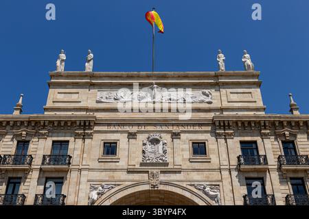 Santander, Spanien. Das zweiflügelige Banco de Santander-Gebäude wird von einem monumentalen Bogen über der Straße mit neoklassizistischen Skulpturen und symmetrischen Ziegelsteinen verbunden Stockfoto