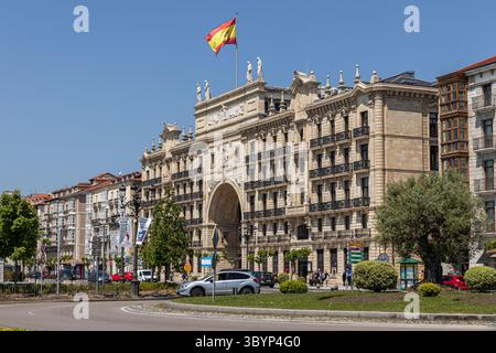 Santander, Spanien. Das zweiflügelige Banco de Santander-Gebäude wird von einem monumentalen Bogen über der Straße mit neoklassizistischen Skulpturen und symmetrischen Ziegelsteinen verbunden Stockfoto