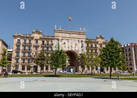 Santander, Spanien. Das zweiflügelige Banco de Santander-Gebäude wird von einem monumentalen Bogen über der Straße mit neoklassizistischen Skulpturen und symmetrischen Ziegelsteinen verbunden Stockfoto