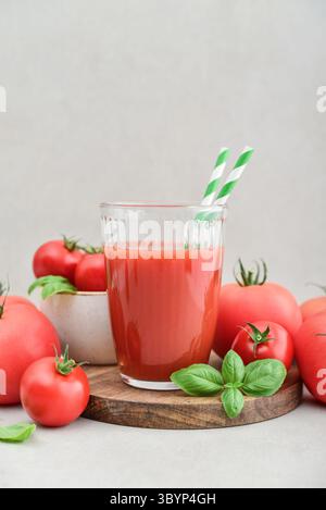 Tomatensaft in einem Glas und frische Tomaten auf hellem Hintergrund Stockfoto