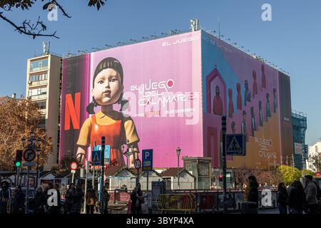 Madrid, Spanien. Das Gebäude der Atocha Street ist mit einer riesigen Plakatwand für die Squid Game Season?2 umhüllt, mit lebendigen Bildern, die die Fassade unter einem klaren Licht bedecken Stockfoto