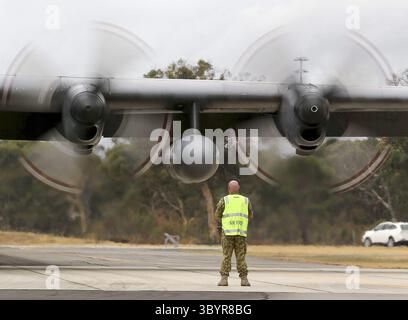 XRG115. Perth (Australien), 29.03.2014.- Ein am 30. März 2014 zur Verfügung gestelltes Bild zeigt einen Bodenbesatzungsmann der Royal Australian Air Force (RAAF), der vor den fahrenden Propellern einer Royal Malaysian Air Force C-130 Hercules steht, nachdem dieser am 29. März 2014 auf der RAAF-Basis Pearce landete, um bei der Suche nach Trümmern oder Trümmern des vermissten Malaysia Airlines Fluges MH370 in Perth, Western Australia, Australien, zu helfen. Schiffe, die nach dem vermissten Flug MH370 suchen, haben schwimmende Objekte aus dem Indischen Ozean gefunden, aber sie waren nicht mit dem verlorenen Jet verwandt, sagten die australischen Behörden am 29. März 2014. Bis Stockfoto