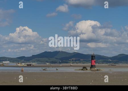Seosan, Südkorea. 13. September 2020: Roter und schwarzer Leuchtturm auf matschigen Gezeiten bei Ebbe im Seosan Harbour unter wolkenblauem Himmel Stockfoto