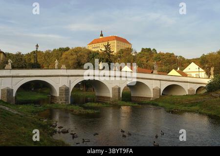 Wunderschönes altes Schloss mit einer Brücke über den Fluss bei Sonnenuntergang. Alte europäische Architektur. Namest nad Oslavou - eine Stadt in der Tschechischen Republik Stockfoto