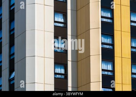 Moderner Hochbau mit strukturierten vertikalen Panels und reflektierenden Fensterbändern Stockfoto