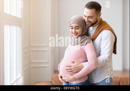 Muslim Paar wartet auf EIN Baby, umarmt stehen zu Hause Stockfoto