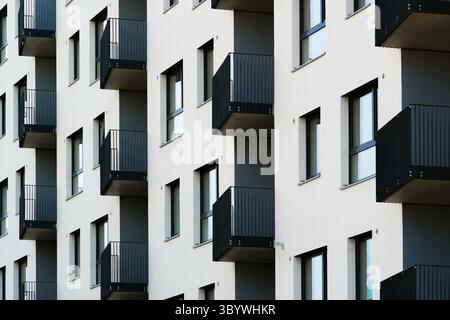 Moderne Apartmentfassade mit hellen Wänden und eingelassenen schwarzen Metallbalkonen Stockfoto