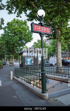 Ein klassisches Pariser Metro-Eingangsschild im Jugendstil am Bahnhof Argentin, umgeben von üppig grünen Bäumen in Frankreich. Stockfoto