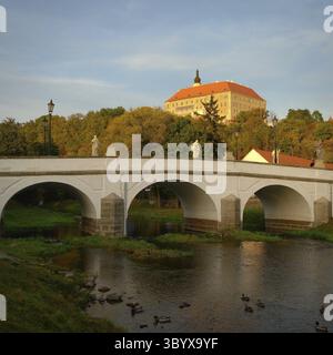 Wunderschönes altes Schloss mit einer Brücke über den Fluss bei Sonnenuntergang. Alte europäische Architektur. Namest nad Oslavou - eine Stadt in der Tschechischen Republik Stockfoto
